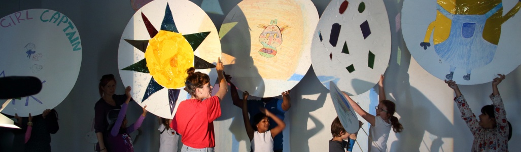 Children hold up large pieces of artwork