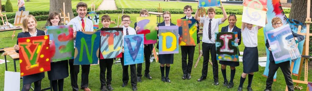 Students hold up spray painted artwork