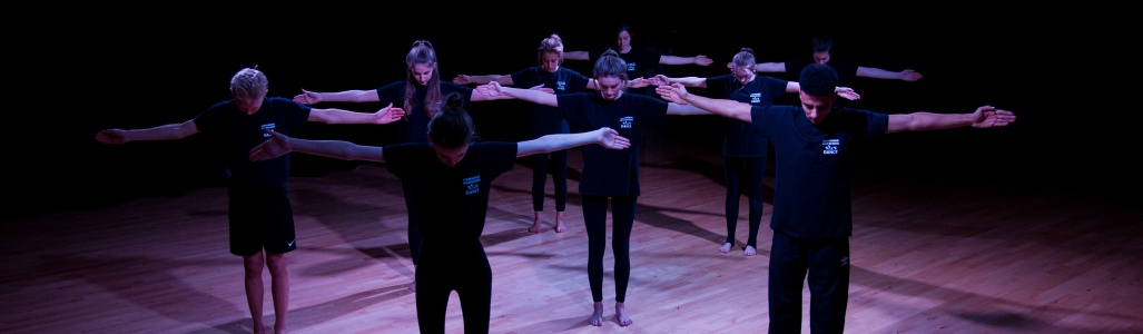 Young people perform a dance on dimly lit stage